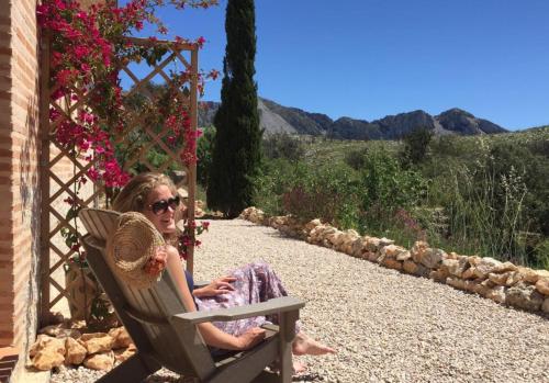 a woman sitting in a chair in a garden at Can Elisa in Tárbena