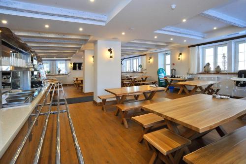 un restaurante con mesas de madera, bancos y ventanas en Hotel Yamskaya, en Zavidovo