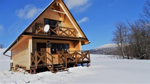 a log cabin in the snow with snow covered at Maniówka - pokoje i domki w Bieszczadach in Maniów