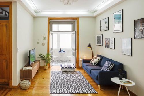 a living room with a blue couch and a tv at Alma de Santos Apartment in Lisbon