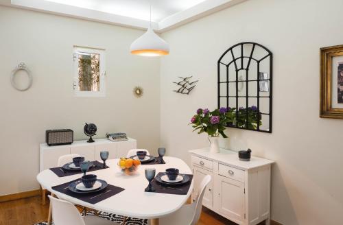 uma sala de jantar branca com uma mesa e cadeiras brancas em Alma de Santos Apartment em Lisboa