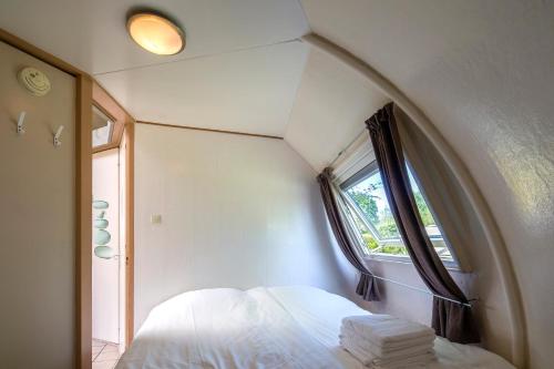 um quarto com uma janela e uma cama com lençóis brancos em Iglo Bungalow 18 em Chaam