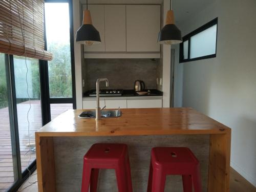 a kitchen with a wooden island with two red stools at Agua y Manto in La Pedrera