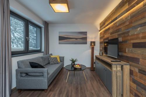 a living room with a couch and a tv at Hotel Královka in Bedřichov