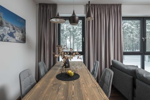 a dining room with a wooden table and a couch at Hotel Královka in Bedřichov