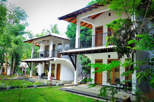 a large white house with balconies and a yard at Kithmi Resort in Polonnaruwa