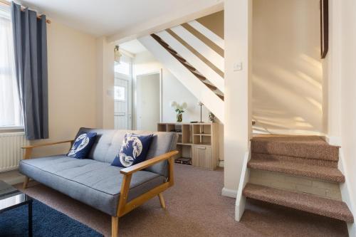 a living room with a blue couch and stairs at Well presented 2 bedroom house - sleeps four in Leamington Spa