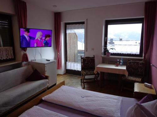 a living room with a couch and a tv on the wall at Pension Schamberger in Neukirchen beim Heiligen Blut