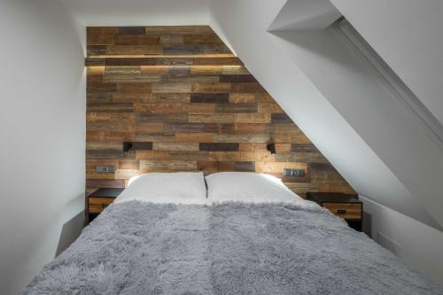 a bedroom with a bed with a wooden wall at Hotel Královka in Bedřichov
