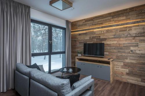 a living room with a couch and a flat screen tv at Hotel Královka in Bedřichov