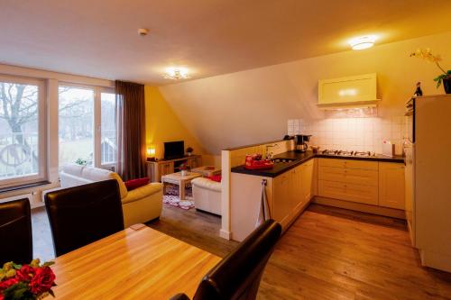 a kitchen and a living room with a couch and a table at De Valkhoeve in Mill
