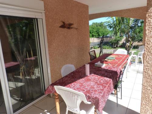 y balcón con mesa de comedor y sillas. en Chez Chouchou, en Rivière