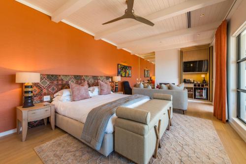 a bedroom with a large bed with an orange wall at La Petite Ferme in Franschhoek