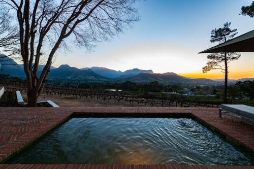 a swimming pool with a sunset in the background at La Petite Ferme in Franschhoek