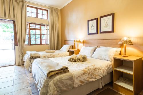 a bedroom with two beds with towels on them at Treetops Guesthouse in Port Elizabeth
