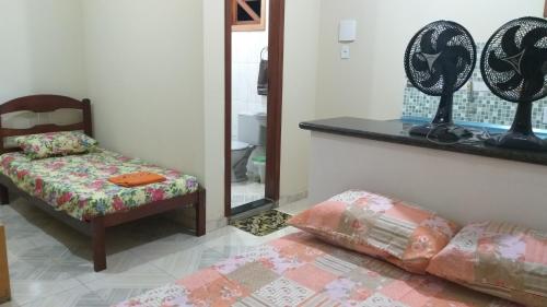 a bedroom with a bed and a mirror and a chair at Azul Kitnets in Santa Cruz Cabrália
