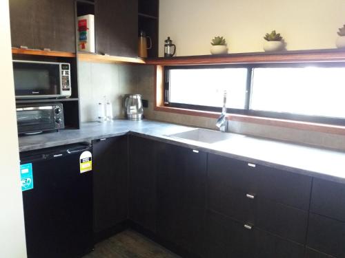 a kitchen with a sink and a microwave at Forest Lodge: Little Villa in Agnes Water