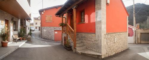 a red building with a staircase on the side of a street at Apartamentos Rurales Les Martes in Felechosa