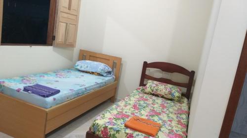 two beds in a small room with a bed and a bedskirts at Azul Kitnets in Santa Cruz Cabrália