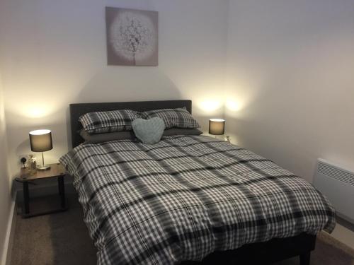 a bedroom with a bed with a plaid blanket and two lamps at St Leonards cottage in Newark upon Trent