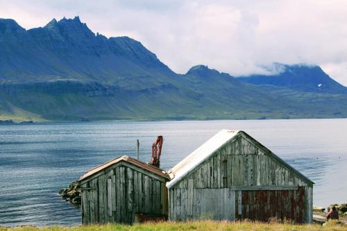 an old building sitting on the side of a body of water at Urdartindur Guesthouse and Cottages in Norðurfjörður