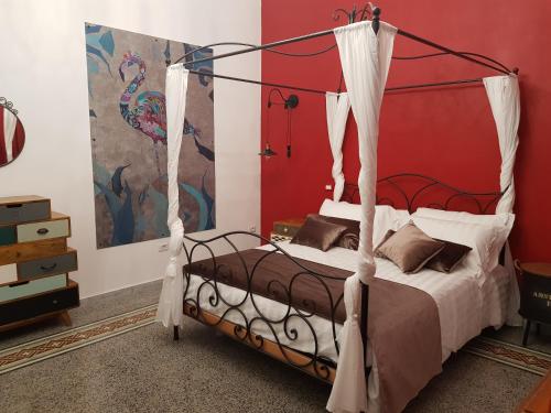1 dormitorio con cama con dosel y pared roja en Lavanera Home, en Nápoles
