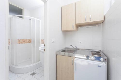 a small white bathroom with a sink and a shower at Guesthouse Mate Ledic in Brela