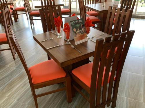 un tavolo e sedie in legno con fiori rossi di Bella Vista Luxury Apartments Nuwara Eliya Sri Lanka a Nuwara Eliya