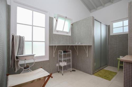 ein Bad mit einer Dusche, einem Waschbecken und Fenstern in der Unterkunft Adega do Mota in Vila Franca do Campo