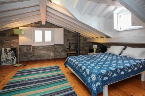 a bedroom with a blue bed in a attic at Adega do Mota in Vila Franca do Campo