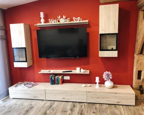 a living room with a flat screen tv on a red wall at Ferienwohnung Auszeit in Ausnang in Leutkirch im Allgäu