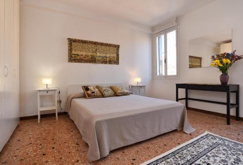 een witte slaapkamer met een bed en 2 tafels bij Appartamento Fabris in Venetië