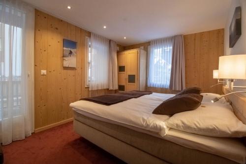 a bedroom with a large bed and two windows at Alpine Lodge in Zermatt