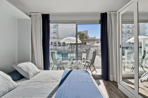 a bedroom with a bed and a balcony with chairs at Carihuela Suites in Torremolinos