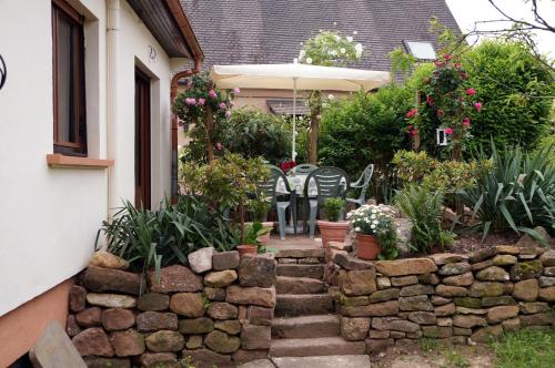 a garden with a stone wall and a table and chairs at Gite Le Mandlé in Riquewihr