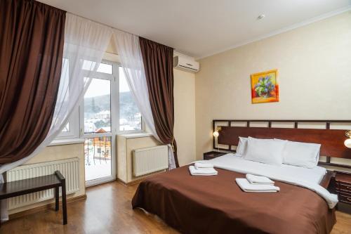 um quarto de hotel com uma cama e uma grande janela em Fantasia Hotel em Polyana