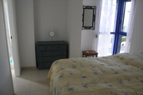 ein Schlafzimmer mit einem Bett, einer Kommode und einem Fenster in der Unterkunft Apartment close to the Beach in Denia