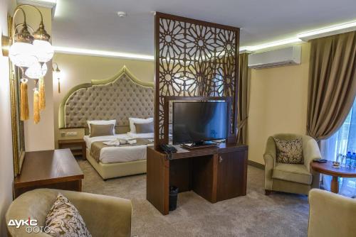 a hotel room with a bed and a flat screen tv at Sahara Hotel in Svilengrad
