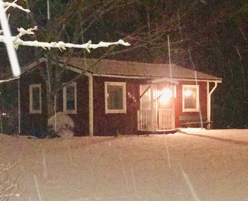 a house with a light on in the snow at Gästhuset i Åselstad 1 in Norrköping
