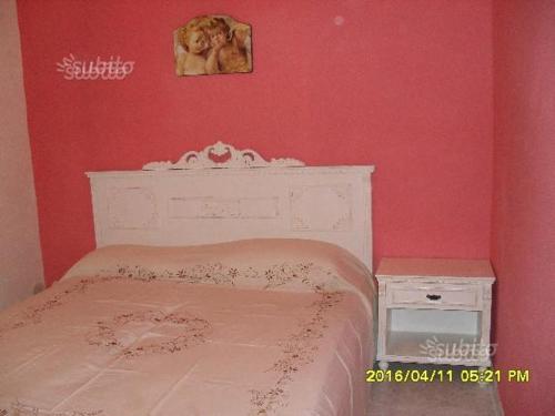 een slaapkamer met een wit bed en een rode muur bij appartamento centro storico in Castelvetrano Selinunte