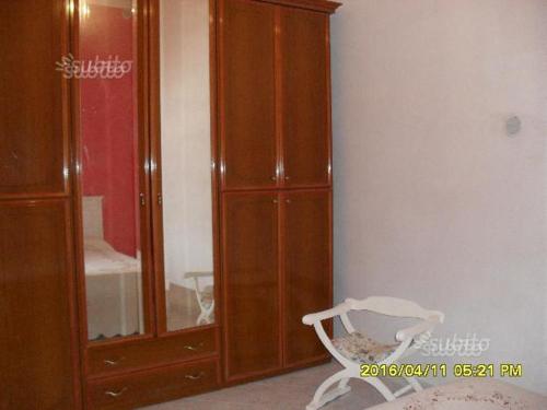 een slaapkamer met een grote houten kast en een stoel bij appartamento centro storico in Castelvetrano Selinunte