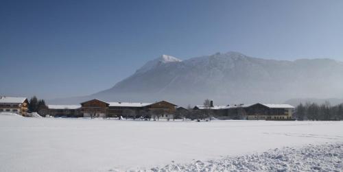 a snow covered field with buildings and a mountain at Chiemgau Appartements in Inzell