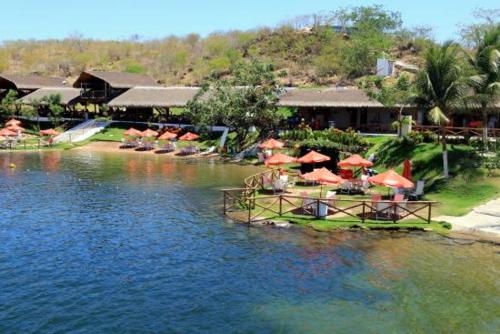 a resort with tables and umbrellas in the water at Casa Família Sena in Piranhas