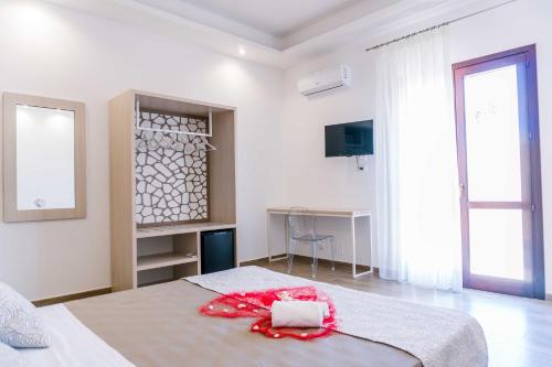 a white bedroom with a bed with a red ribbon on it at B&B Le Tartarughe in San Vito lo Capo