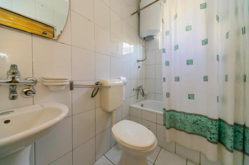 a white bathroom with a toilet and a sink at Apartments Sole Mar in Sutomore