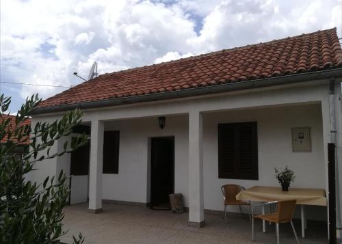 a white house with a table and chairs at Kuća za odmor "Joso" in Puljane