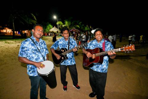three men playing instruments on the beach at night at Sath Villa Naadi Ayurveda Resort in Moragalla