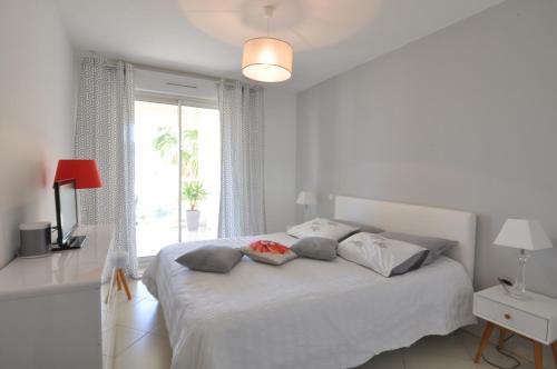 um quarto branco com uma cama e uma janela em Elegant one-bedroom apartment with swimming pool - StayInAntibes - Le Vallon em Antibes