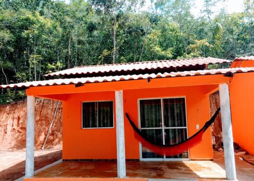 una casa naranja con una hamaca delante de ella en Praia do Jatobá, en São Jorge