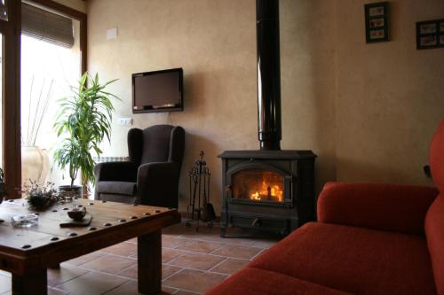 sala de estar con chimenea y TV en La Casa del Azafrán, en Villanueva del Rebollar de la Sierra